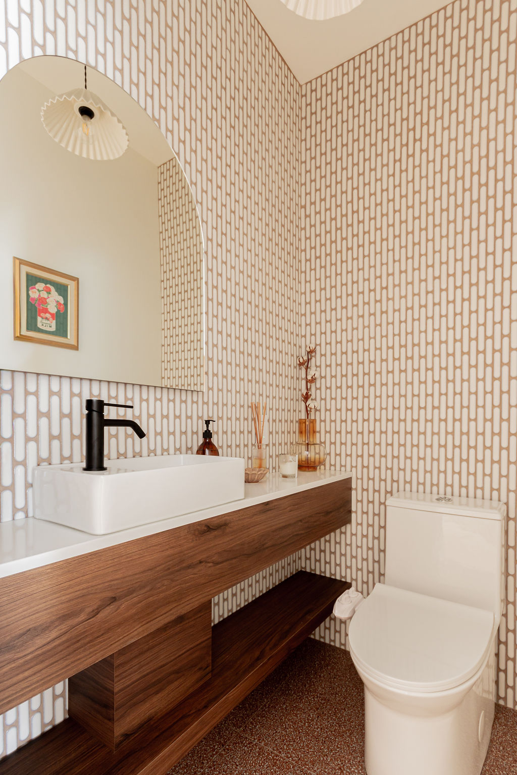 Salle d’eau rénovée à Montréal avec toilettes blanches et bidet, meuble sur mesure en bois style noyer, vasque blanche, robinet noir et mosaïque murale design.