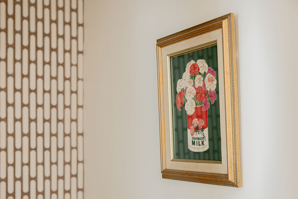 Tableau baroque doré avec boîte de conserve et fleurs dans une salle d’eau rénovée à Montréal par un entrepreneur général et designers d’intérieur.