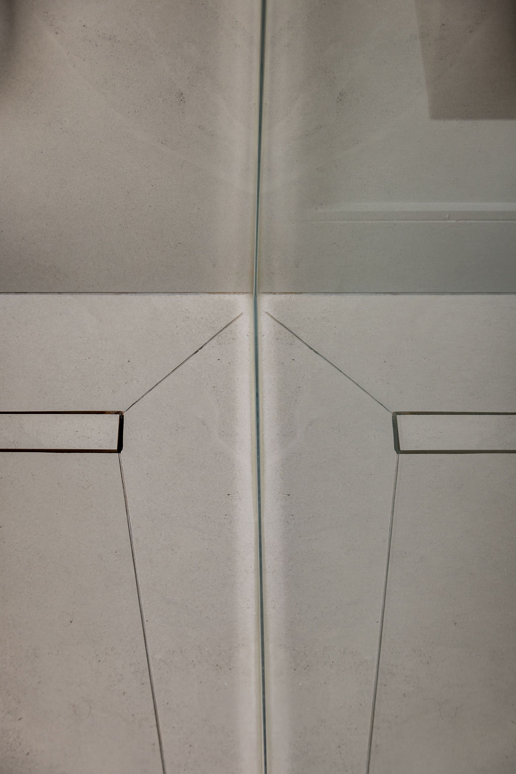 Gros plan sur un drain linéaire encastré et découpe de carrelage en pente pour douche italienne, réalisé par un designer d'intérieur à Montréal.