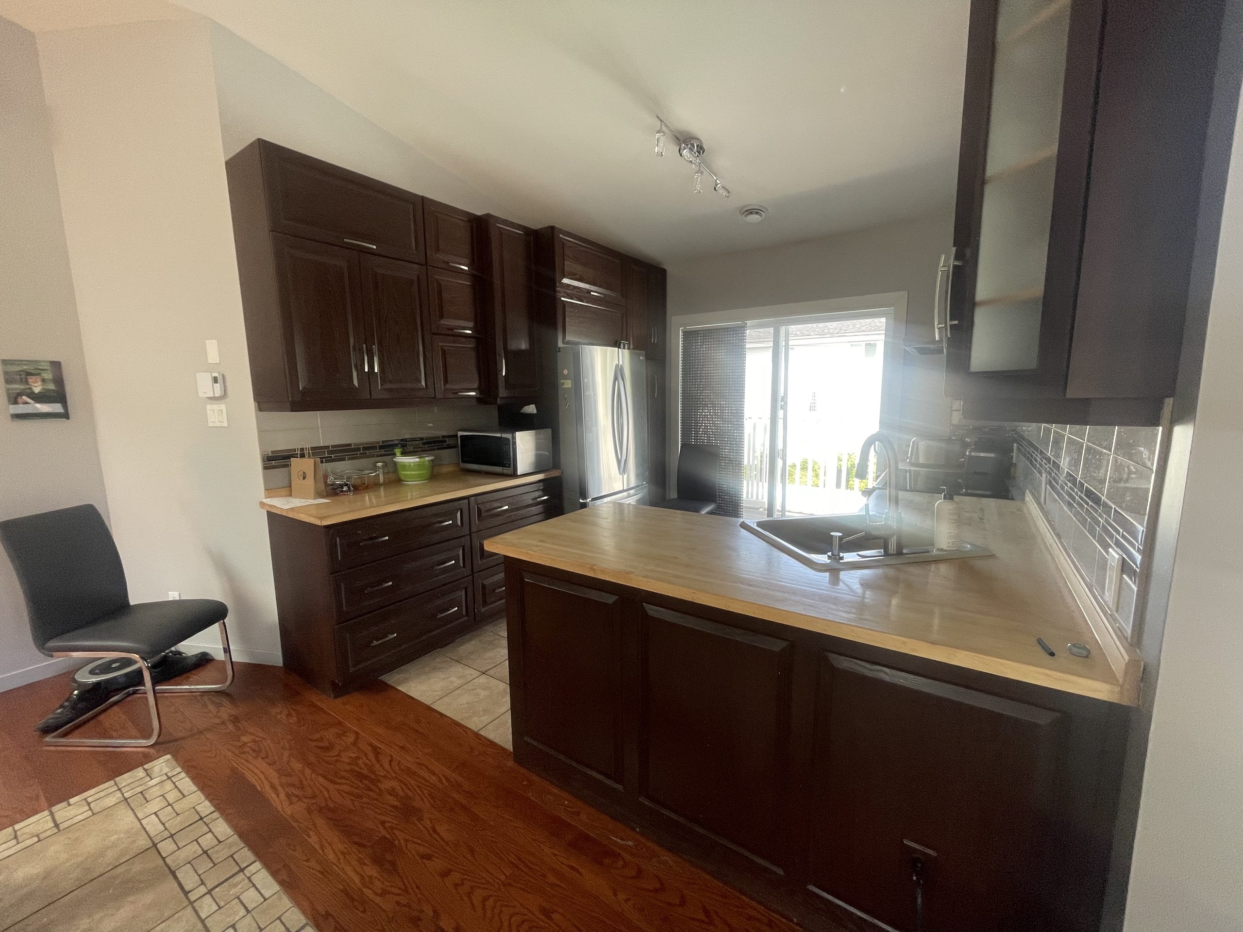 Cuisine traditionnelle à Montréal AVANT la rénovation par un designer d'intérieur : armoires sombres en bois, comptoirs en bloc de boucher et îlot central.